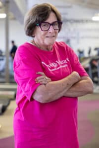 Cheryl poses for a portrait wearing a pink New Heart shirt. 